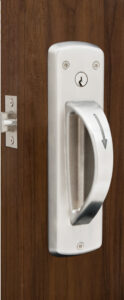 DH415 Ligature-Resistant Door Handle in sleek, stainless steel finish, securely mounted on a behavioral healthcare facility door. The handle features a smooth, sloped design that minimizes ligature risk, providing both safety and durability in high-security environments.