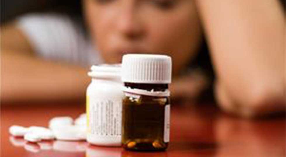 Woman looking at pill bottle dealing with depression